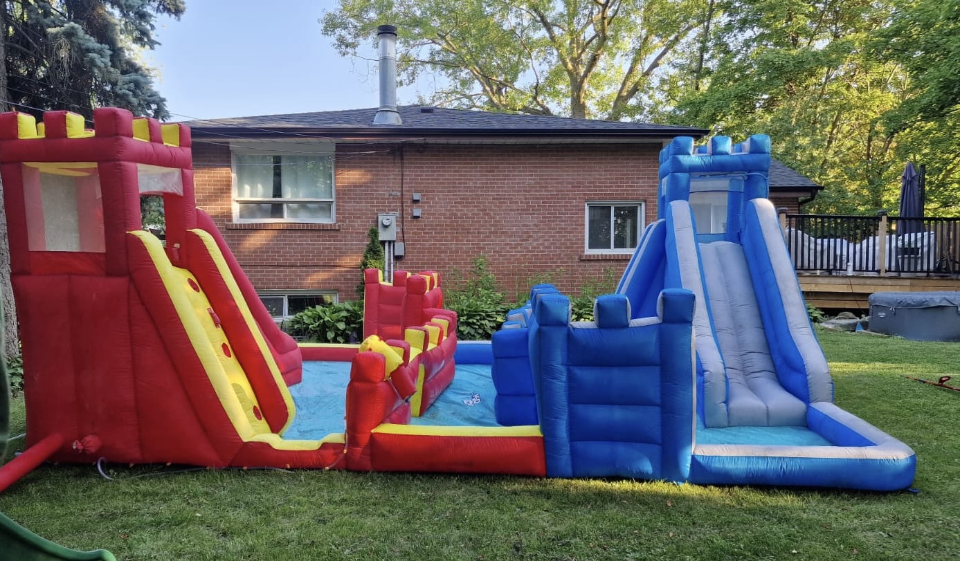 Red and blue inflatable castle with two slides set up on a lawn